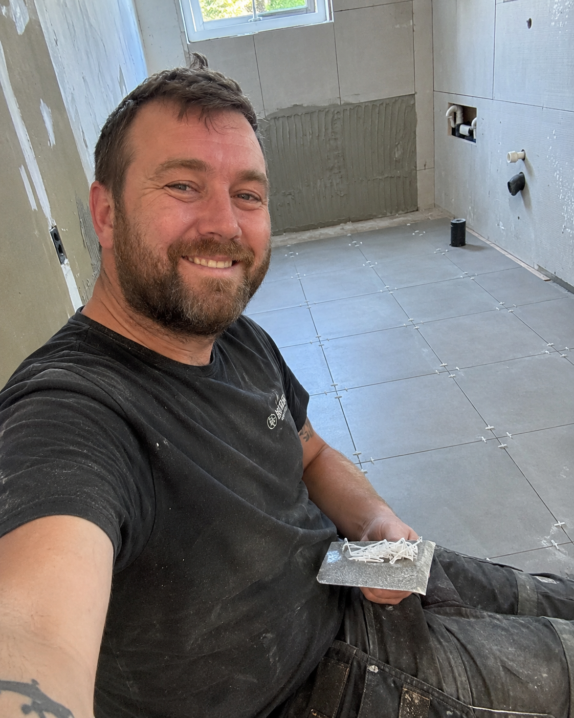 Carreleur souriant sur un chantier de salle de bain